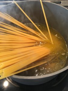 Photo of adding pasta to boiling water. 