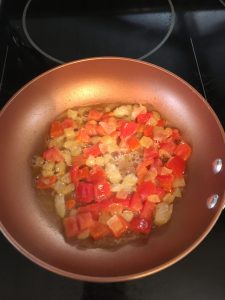 Photo of onion, bell pepper, and tomato cooking.