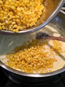 Photo of adding corn to cream sauce.