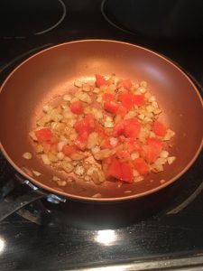 Photo of onions and tomatoes in a pan. 
