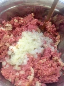 Photo of onions being added to the meatloaf mixture.