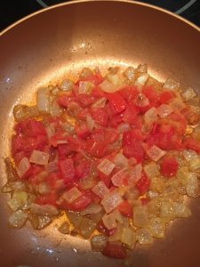 Photo of onions and tomatoes cooking.