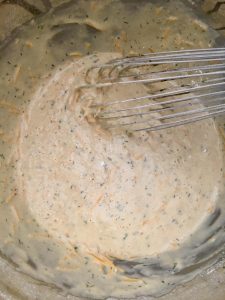 Photo of whisking cheese into batter. 