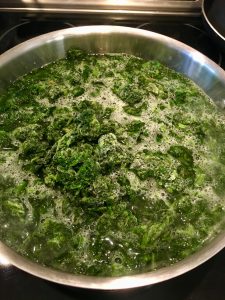 Photo of adding frozen spinach to boiling water. 