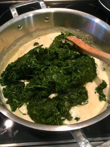 Photo of adding spinach to cream sauce. 