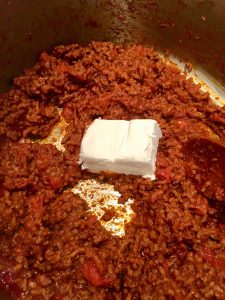 Photo of adding cream cheese to meat sauce.