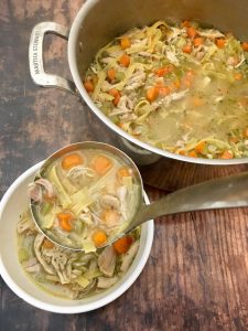 Chicken soup with noodles being served. 