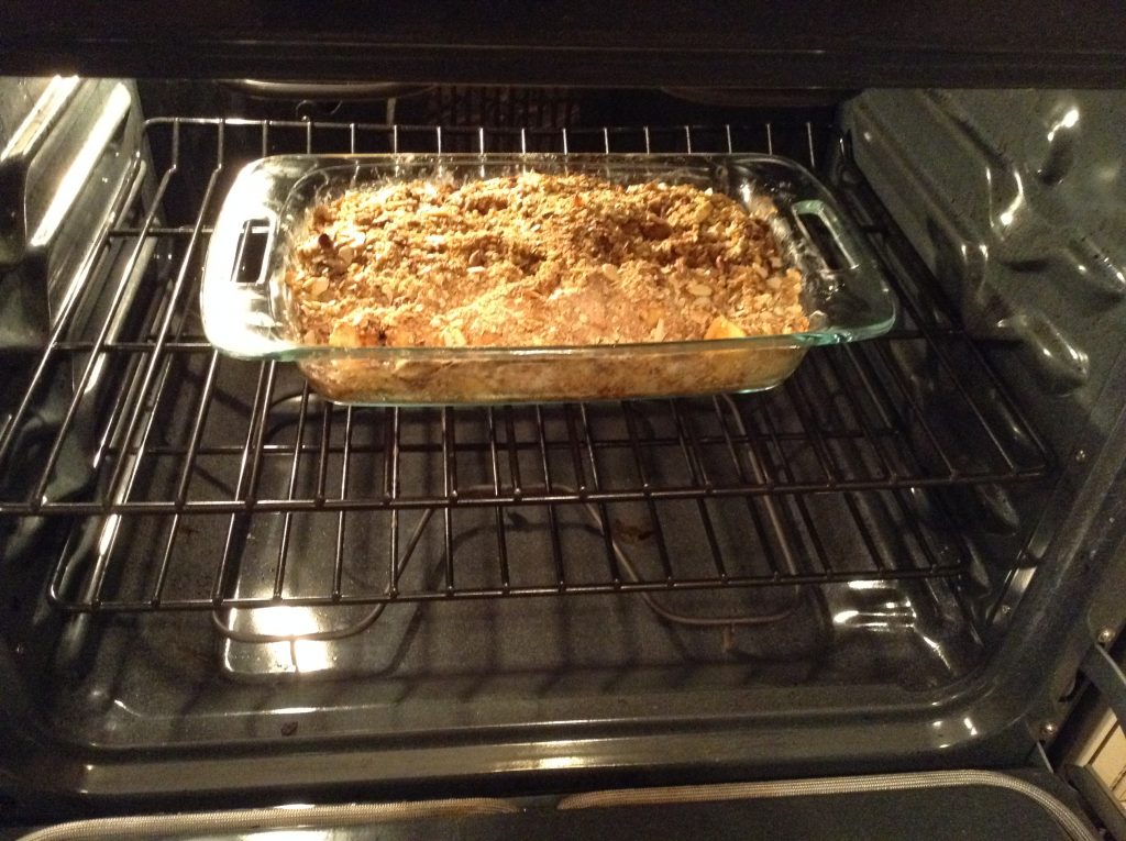 Picture of apple crisp in clear baking dish going into the oven