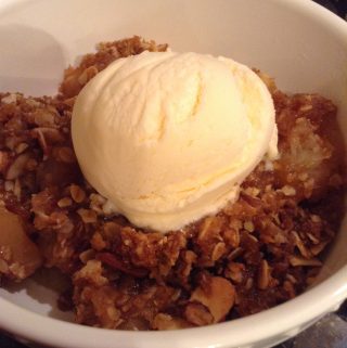 Picture of a single serving of apple crisp a la mode (served with ice cream).