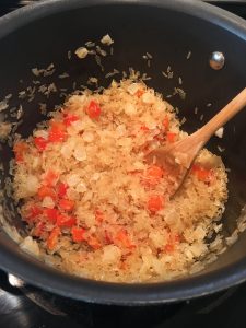 Photo of onions, peppers, and rice cooking. 