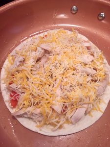 Photo of tortilla with chicken, veggies, and cheese.