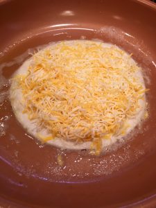 Photo of a tortilla with a pile of triple cheddar cheese.