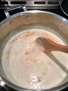 Photo of stirring cheeses into cream sauce.