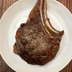 Photo of a bib juicy bone-in rib eye steak.