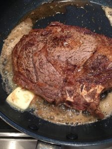 Photo of adding butter to the rib eye steak. 