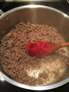 Add tomato paste to ground beef. 
