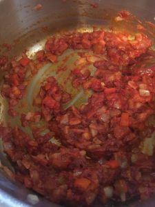 Tomato paste added to cooked onions and bell peppers.