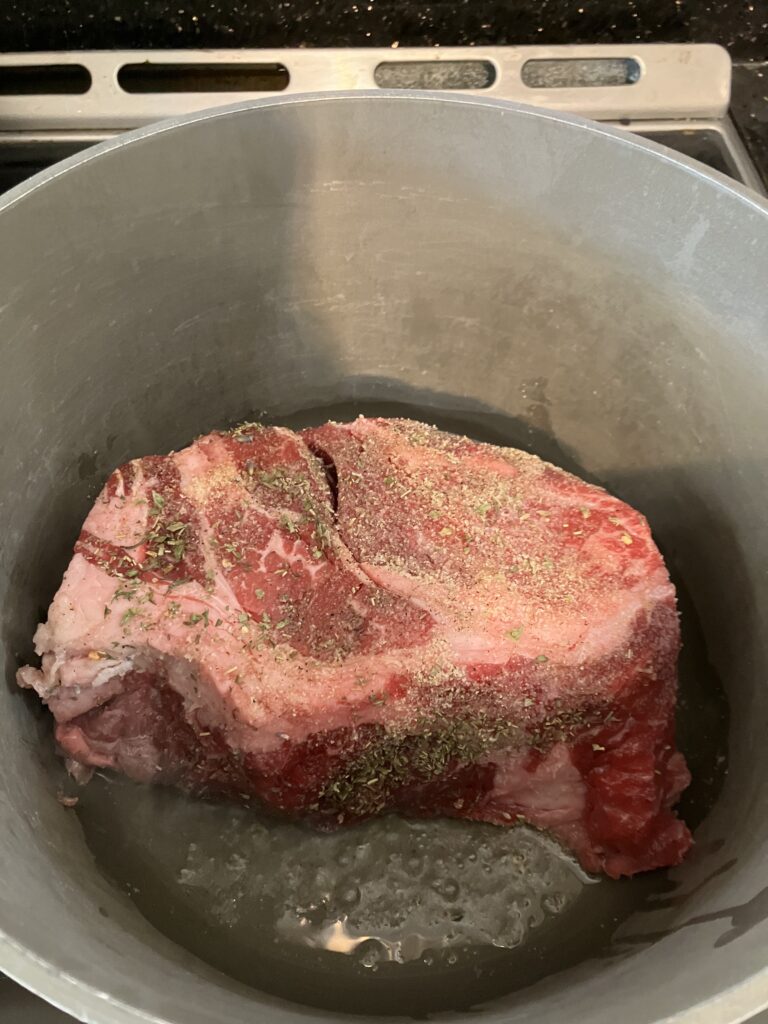 Chuck roast beef searing in a pot for Italian Pot Roast. 