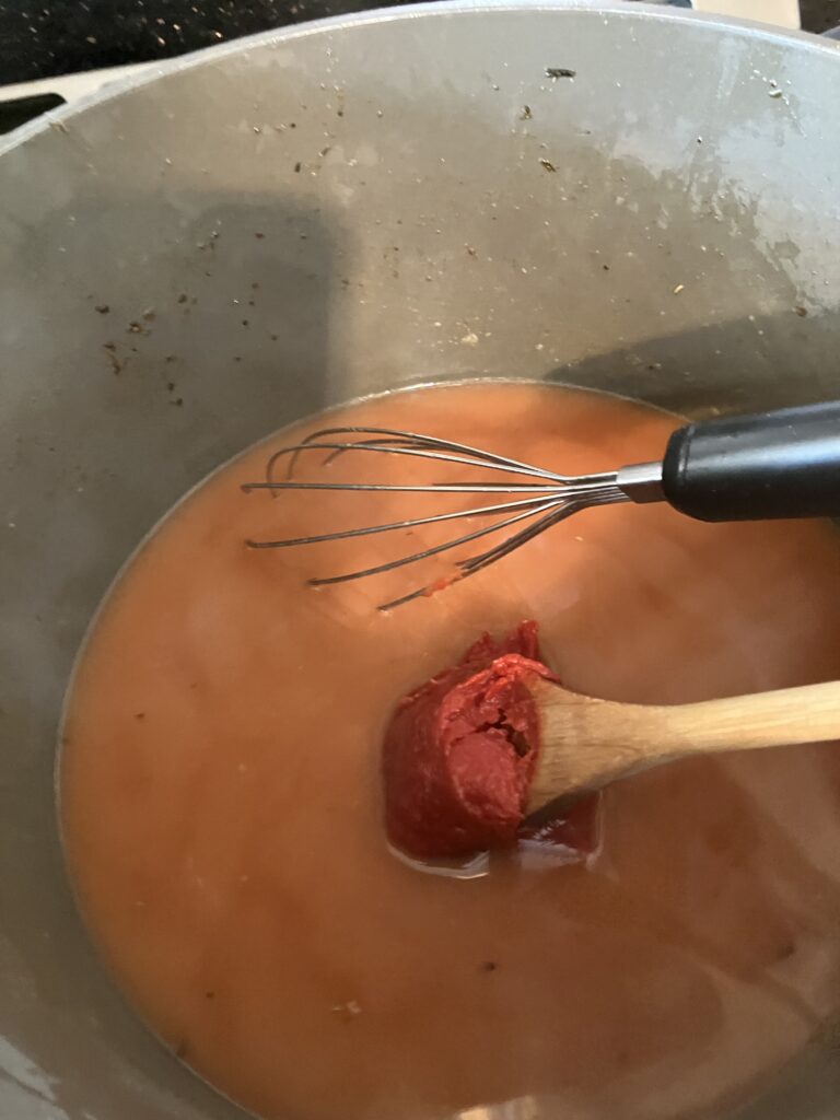 Adding tomato paste to the sauce. 