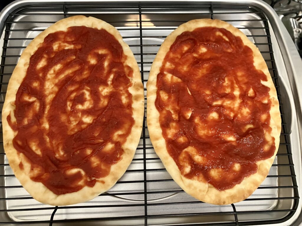 Add tomatoes sauce to flatbreads.