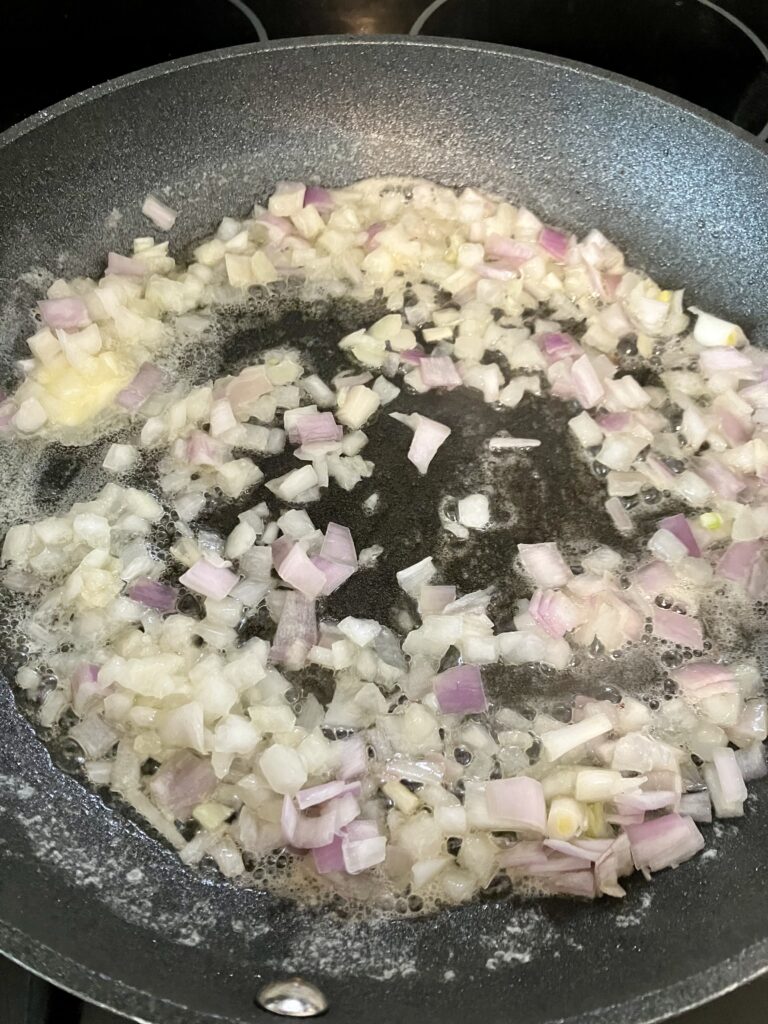 Onions and shallots cooking in a pan.