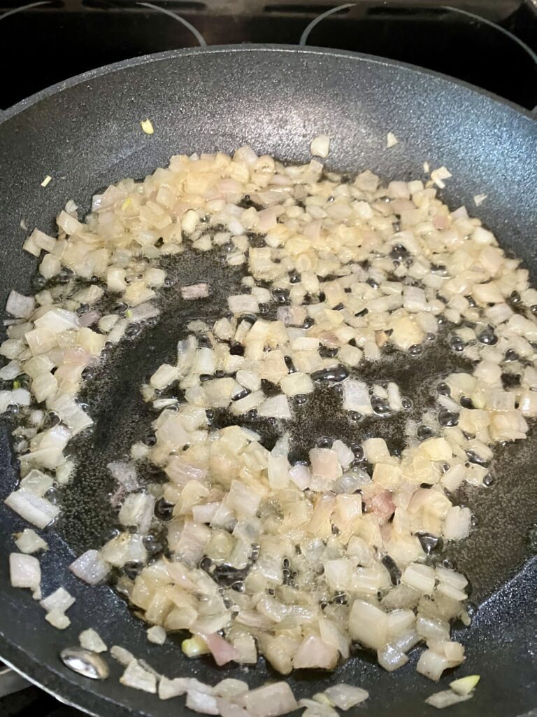 Onions and shallots cooking in a pan.