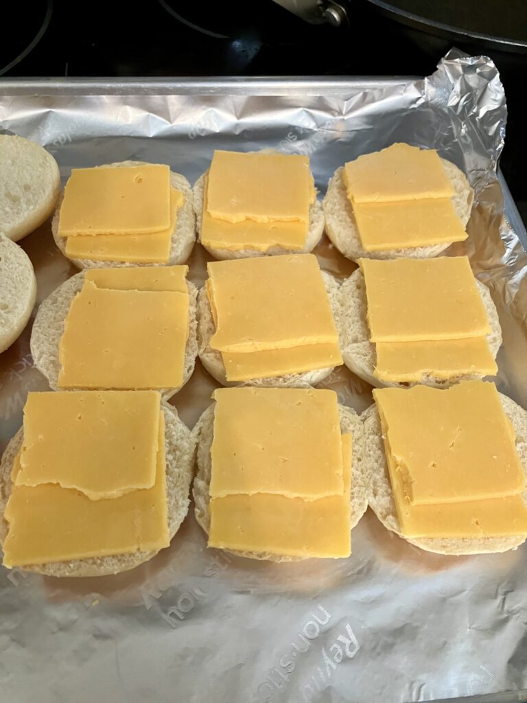 Adding cheese to Hawaiian slider rolls.