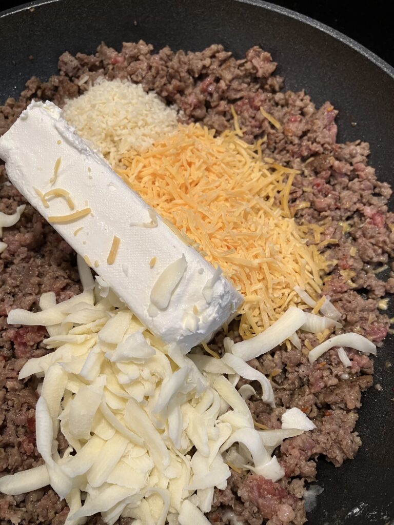 Add cream cheese, cheddar, mozzarella, and gruyere to ground sausage.