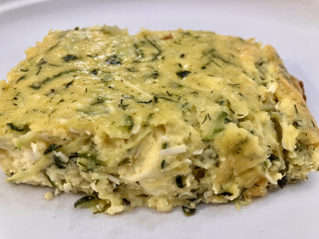 Sfougato is a Greek zucchini, feta cheese, and egg breakfast dish that is baked in the oven.  It's similar to a crustless quiche.