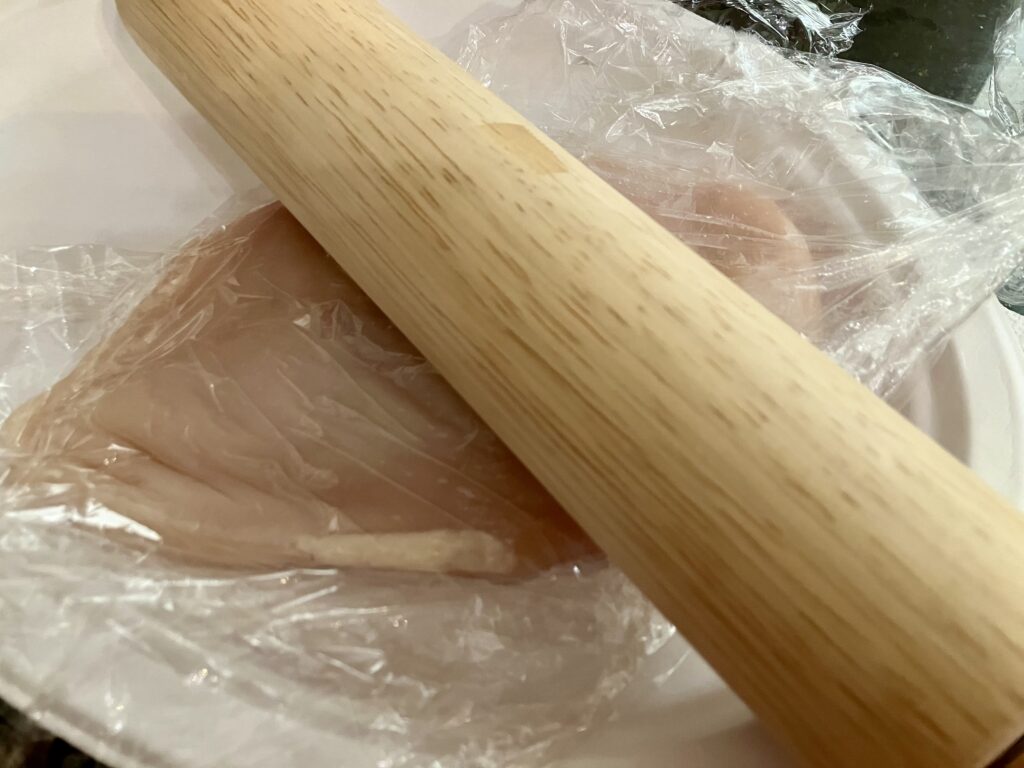 Flattening a chicken breast with a rolling pin. 