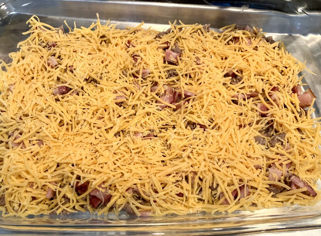 Add shredded cheeses to the ground sausage and bacon. 