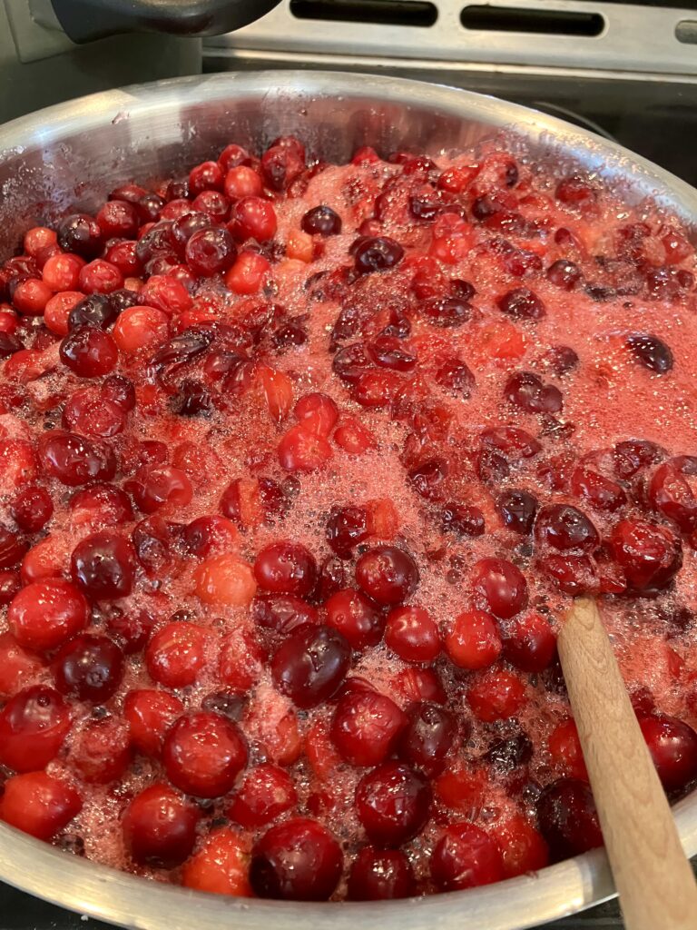 Fresh whole cranberries cooking with cranberry juice, orange juice, sugar, Grand Marnier, Cointreau, Vanilla extract, and ground cinnamon. This photo also demonstrates how quickly this sauce can boil to the top of the pot. 