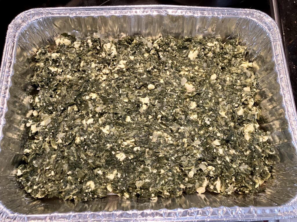 Spanakopita filling in a baking dish. 