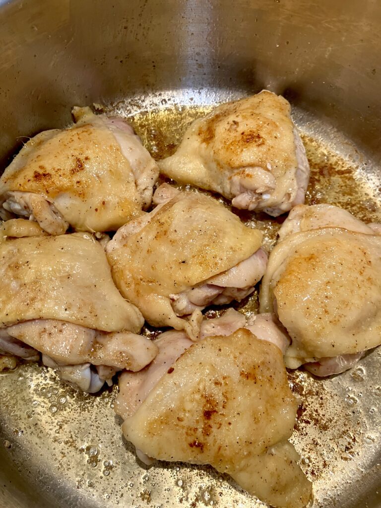 Chicken thighs pieces cooking in a pan. 