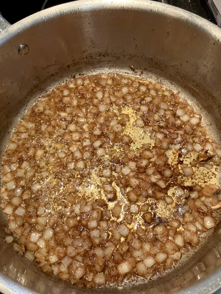 Onions cooking in chicken fat in a pan. 