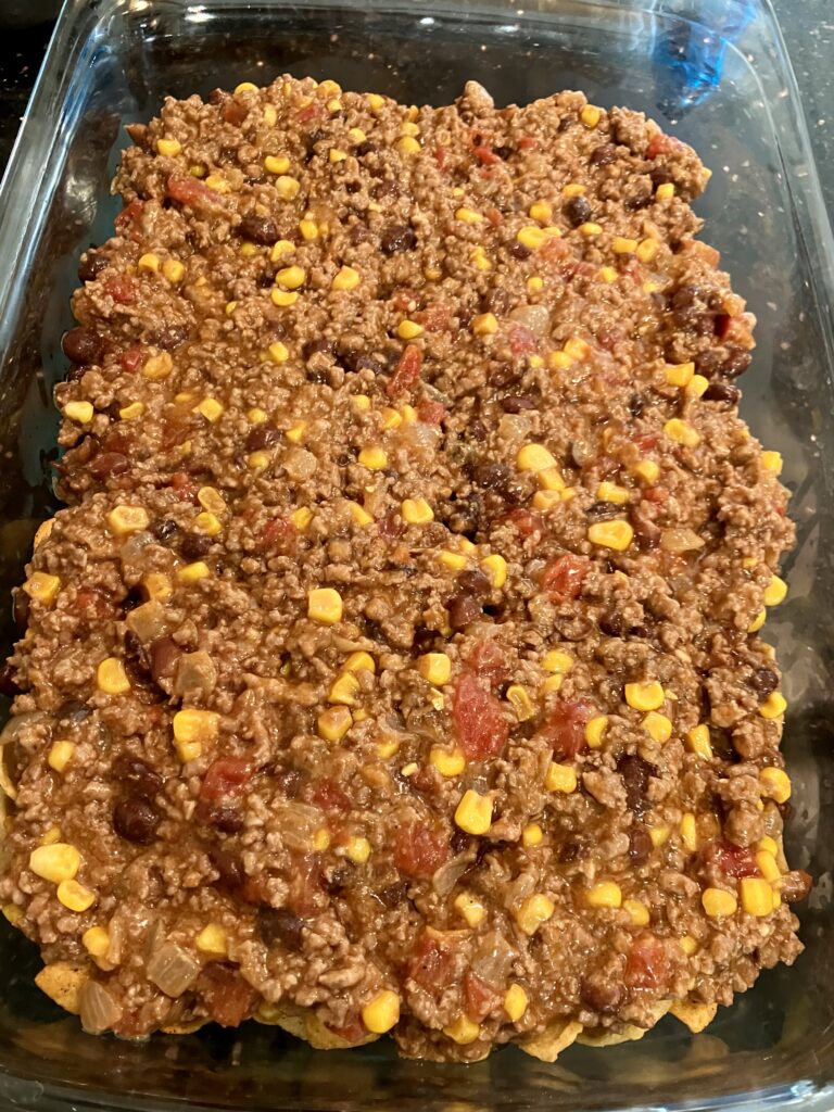 Ground beef, tomato, corn, and black bean sauce over Fritos chips. 